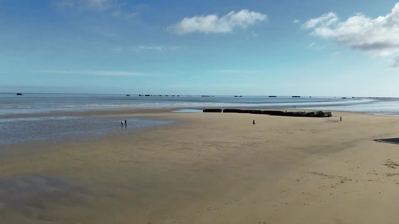 Vue aérienne de la plage d’Arromanches-les-Bains à marée basse, avec les caissons Phoenix du port Mulberry au large.