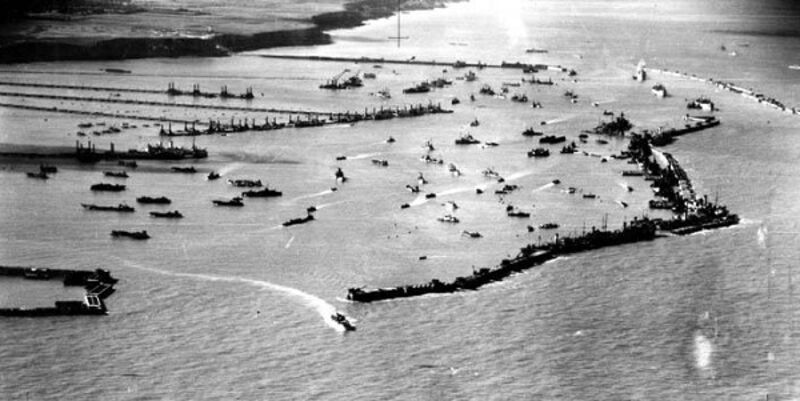 Vue aérienne historique du port artificiel Mulberry en opération à Arromanches : caissons, jetées, navires alliés en cours de déchargement.